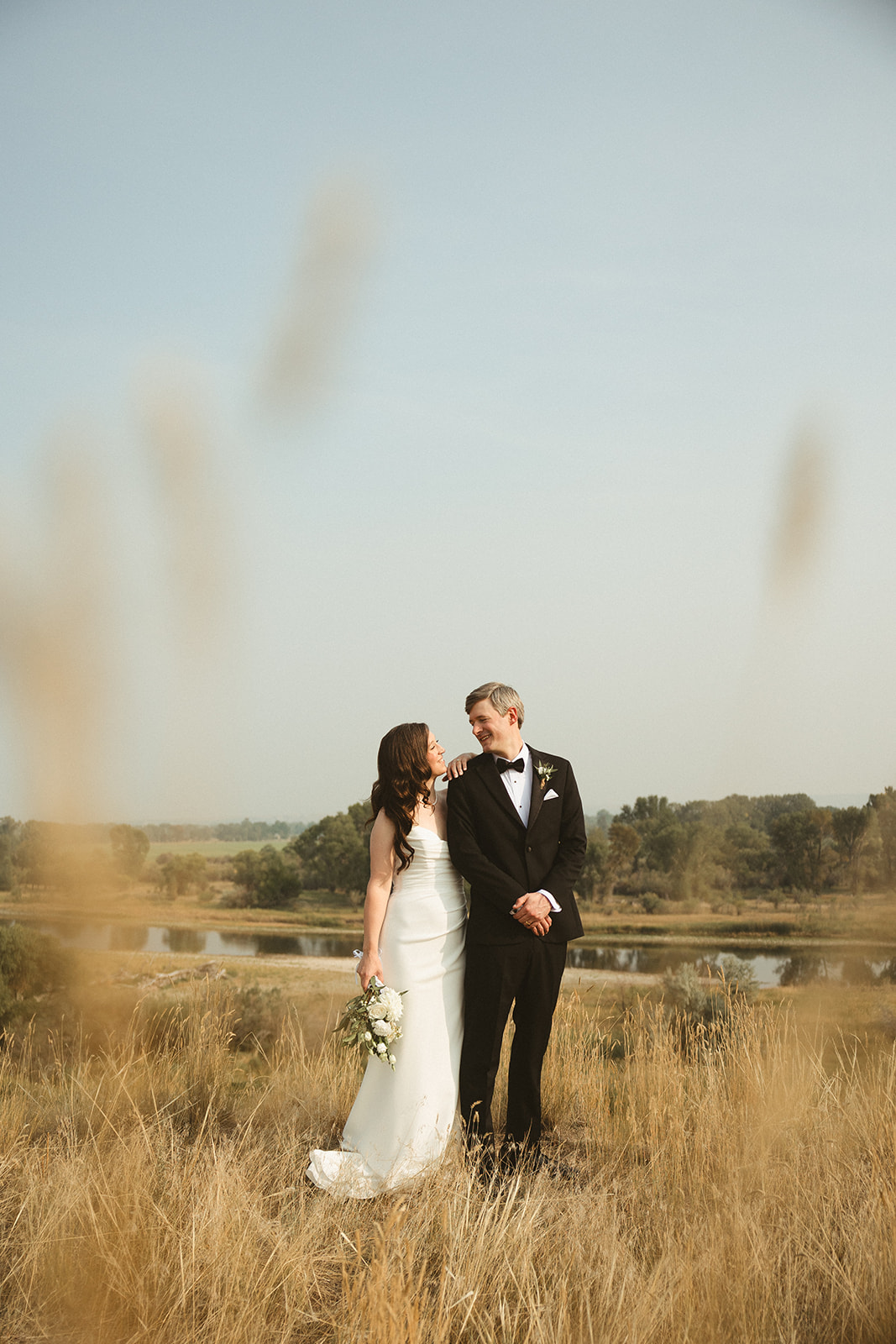 A bride and groom in a field taking wedding photos