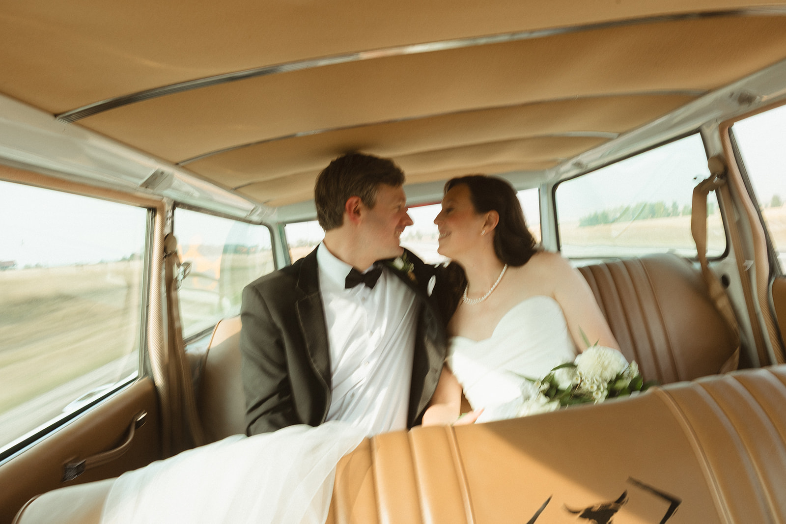 A bride and groom in a wedding getaway car