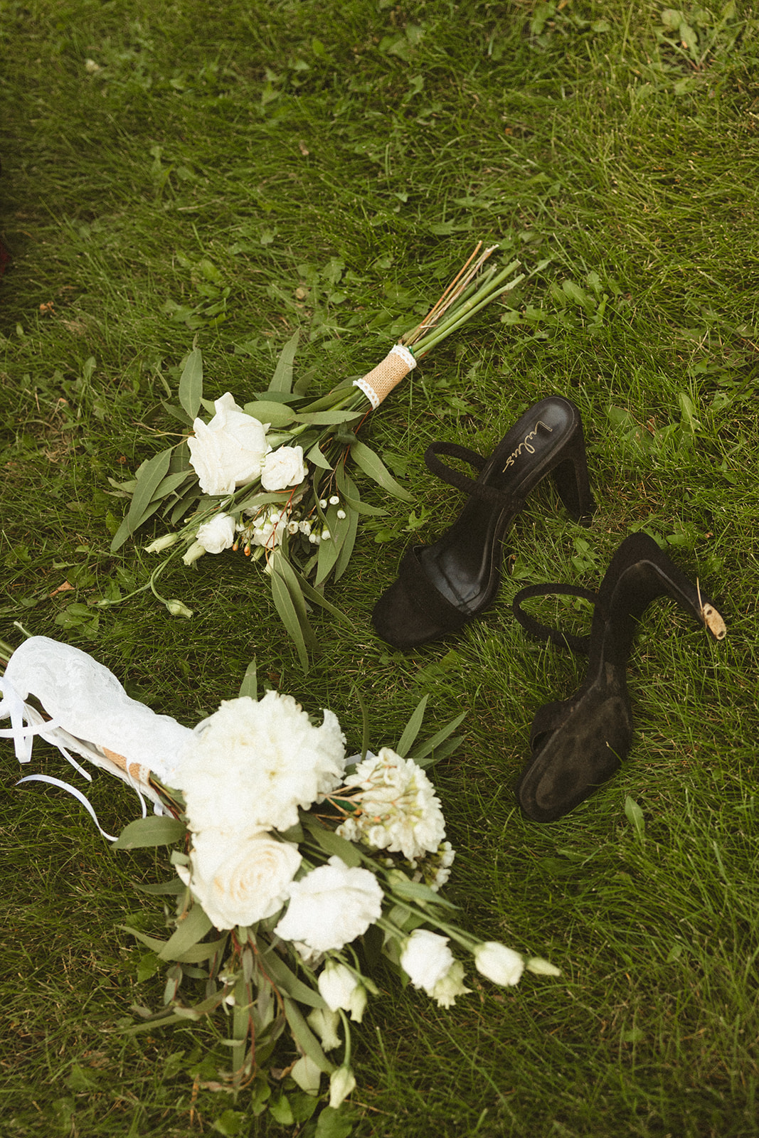 A wedding flat lay in the grass with wedding shoes and flowers