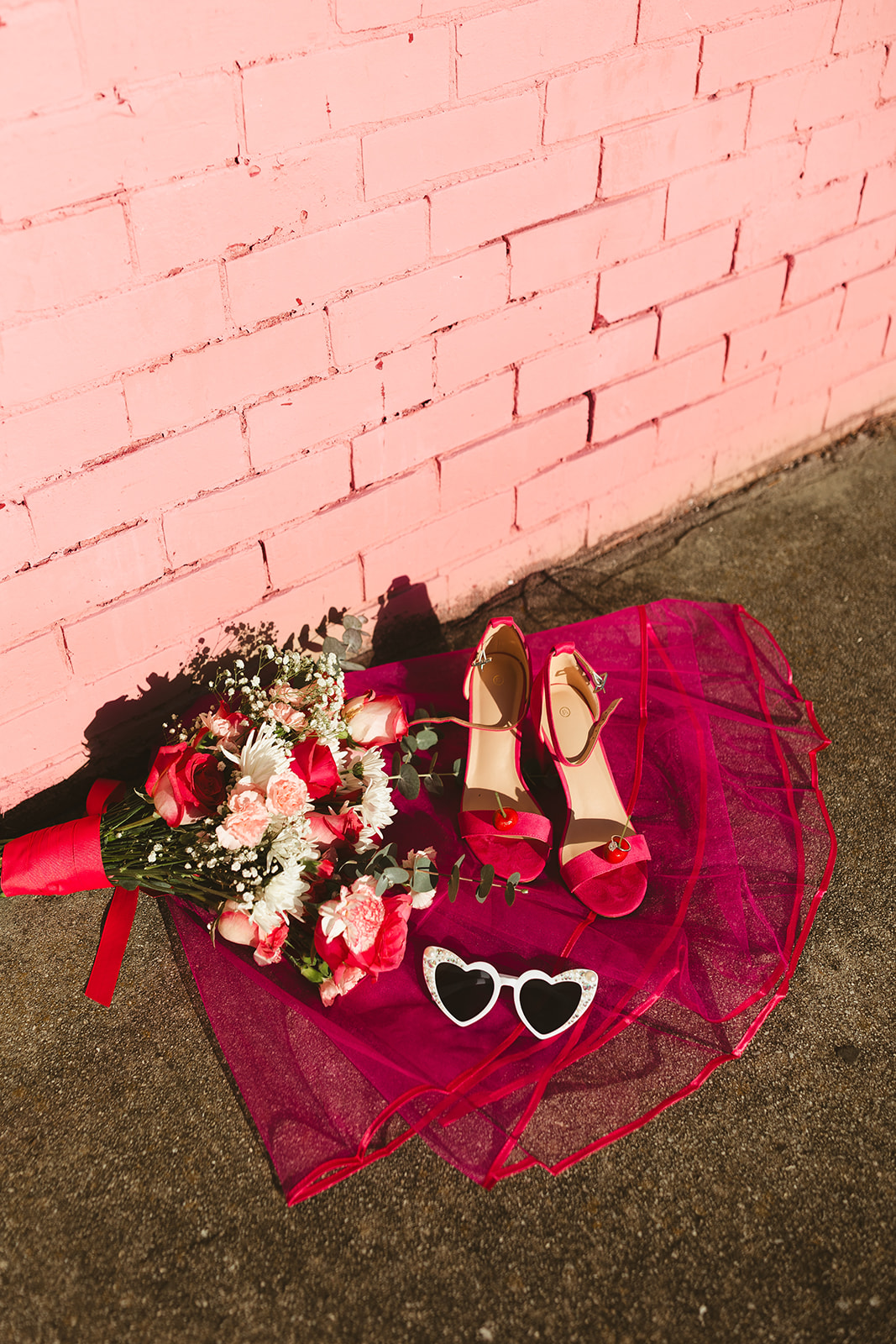 A wedding flat lay with tons of unique wedding ideas, like hot pink shoes and veils and disco balls
