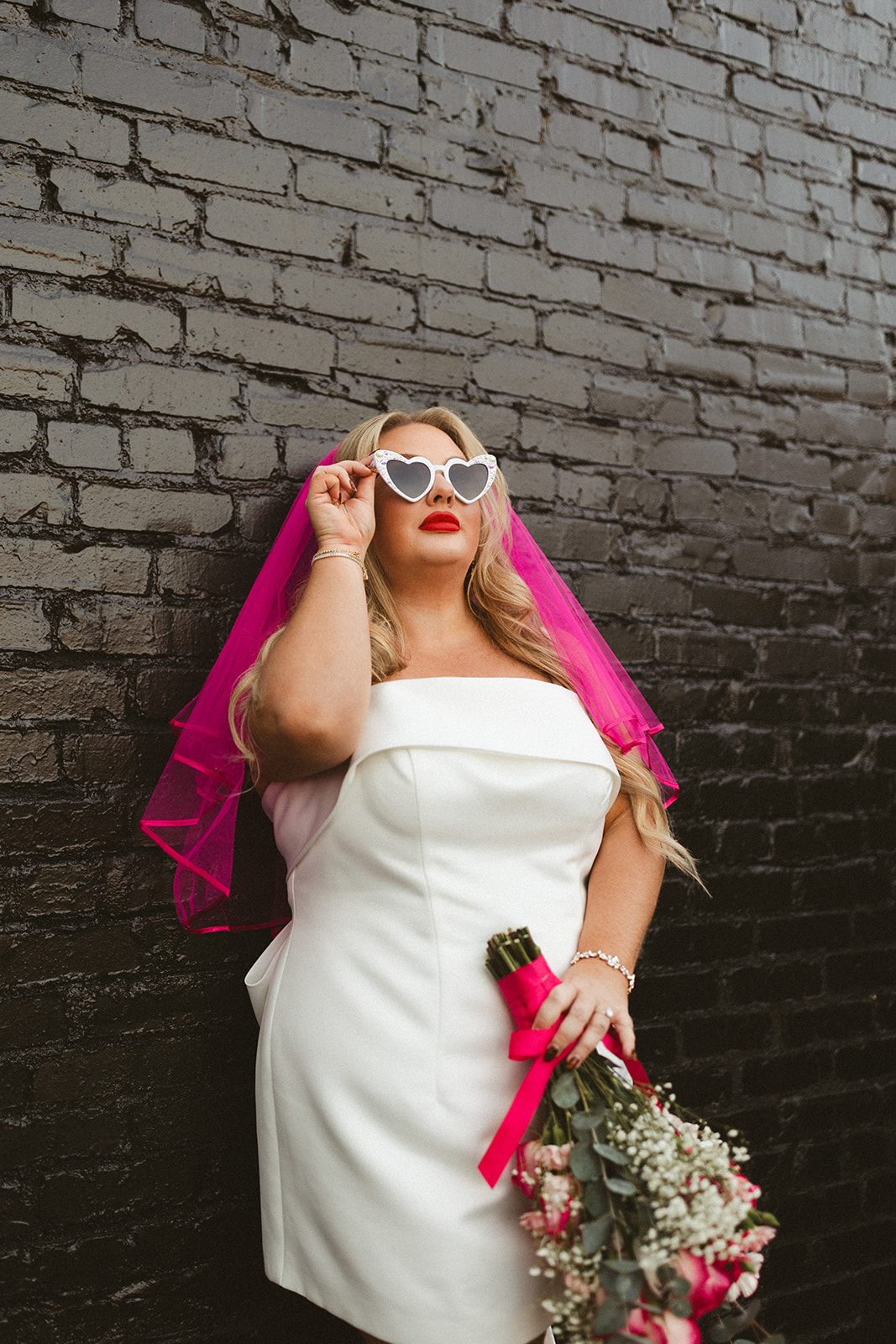 A bride's elopement outfit with a hot pink veil and short dress, perfect as unique wedding ideas