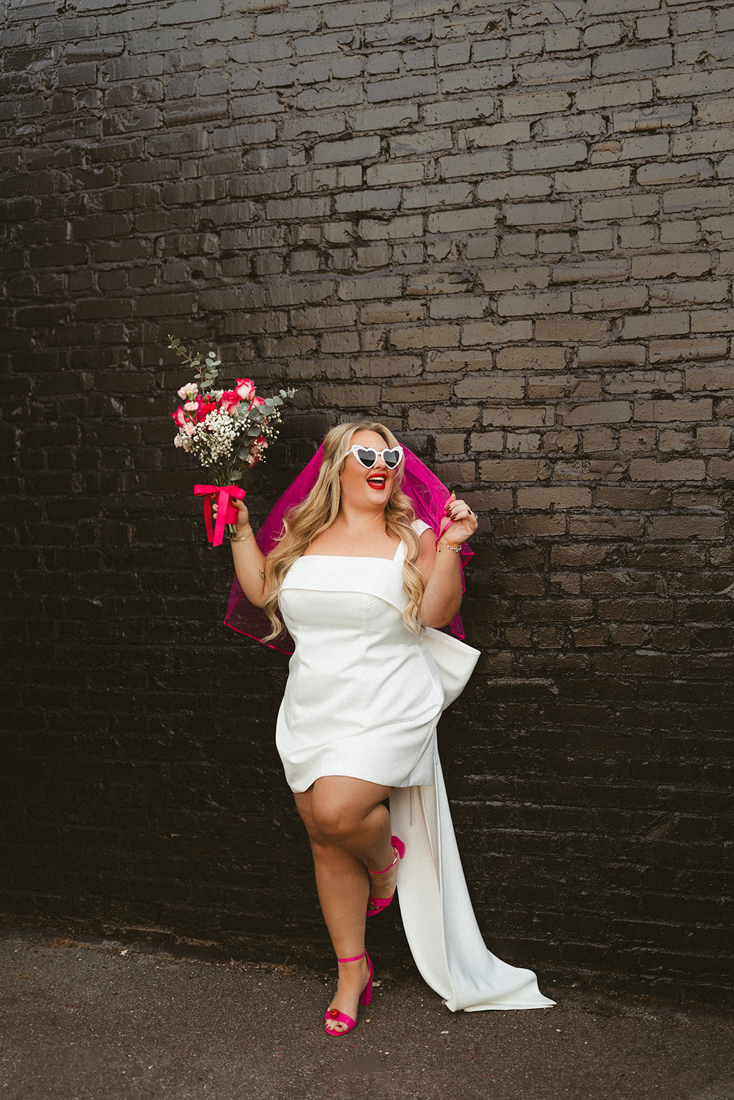 A bride's elopement outfit with a hot pink veil and short dress, perfect as unique wedding ideas