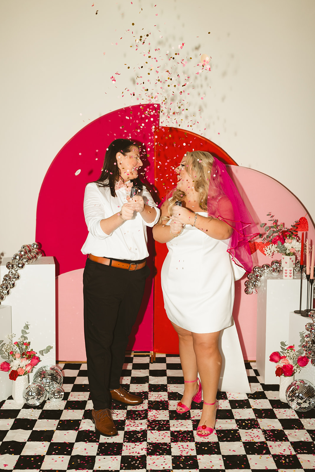 Two brides popping confetti at their valentines themed wedding