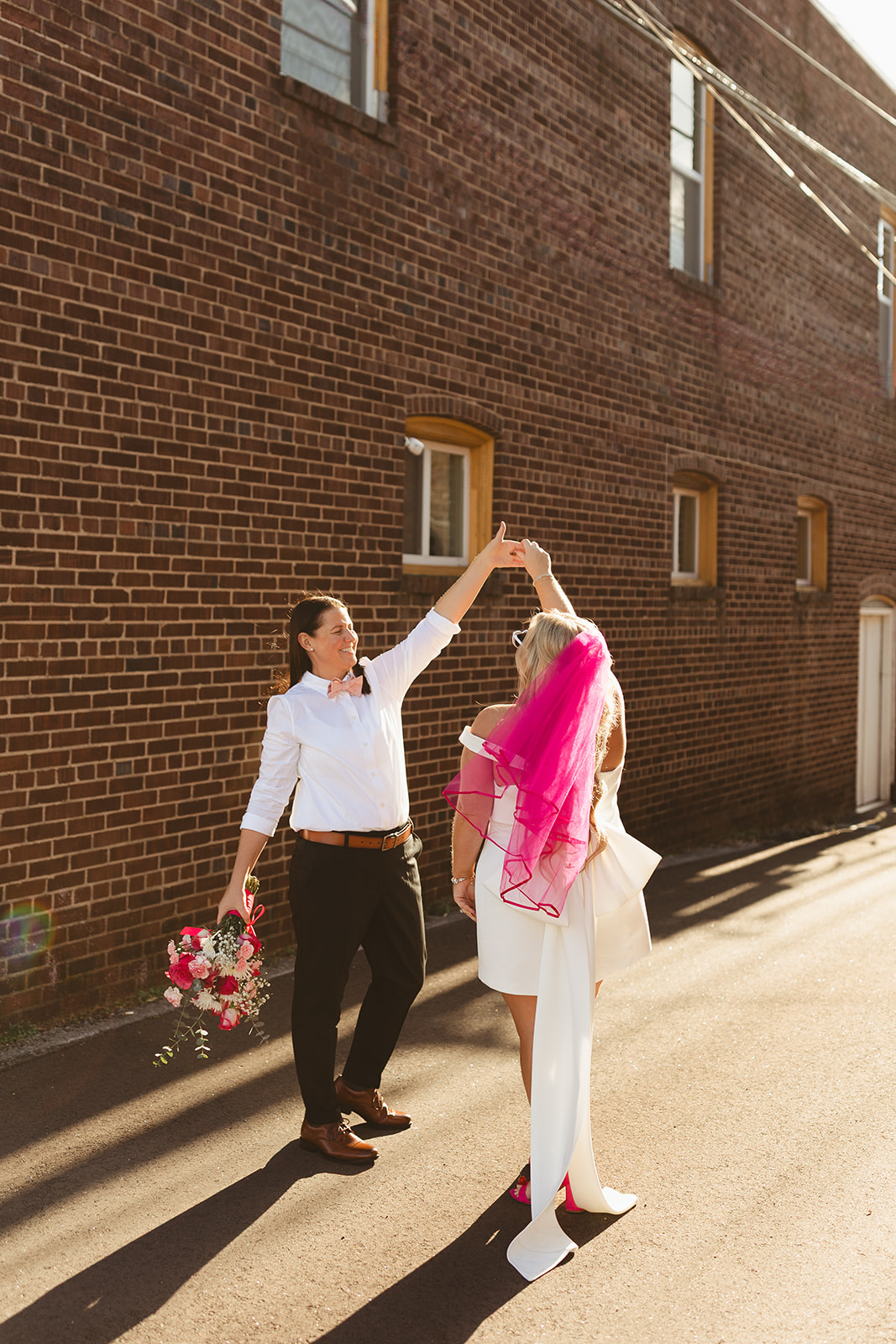 Two brides dancing while taking city street photos as unique wedding ideas