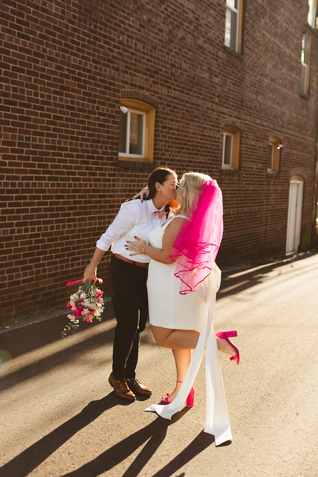 Two brides dancing while taking city street photos as unique wedding ideas