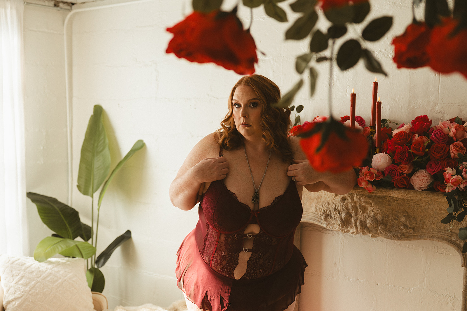 A woman posing for boudoir photos in red lingerie
