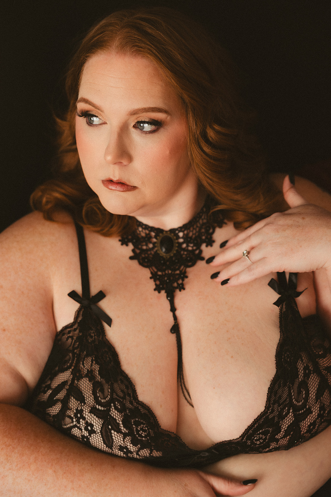A woman posing for her boudoir session in a black lace bra