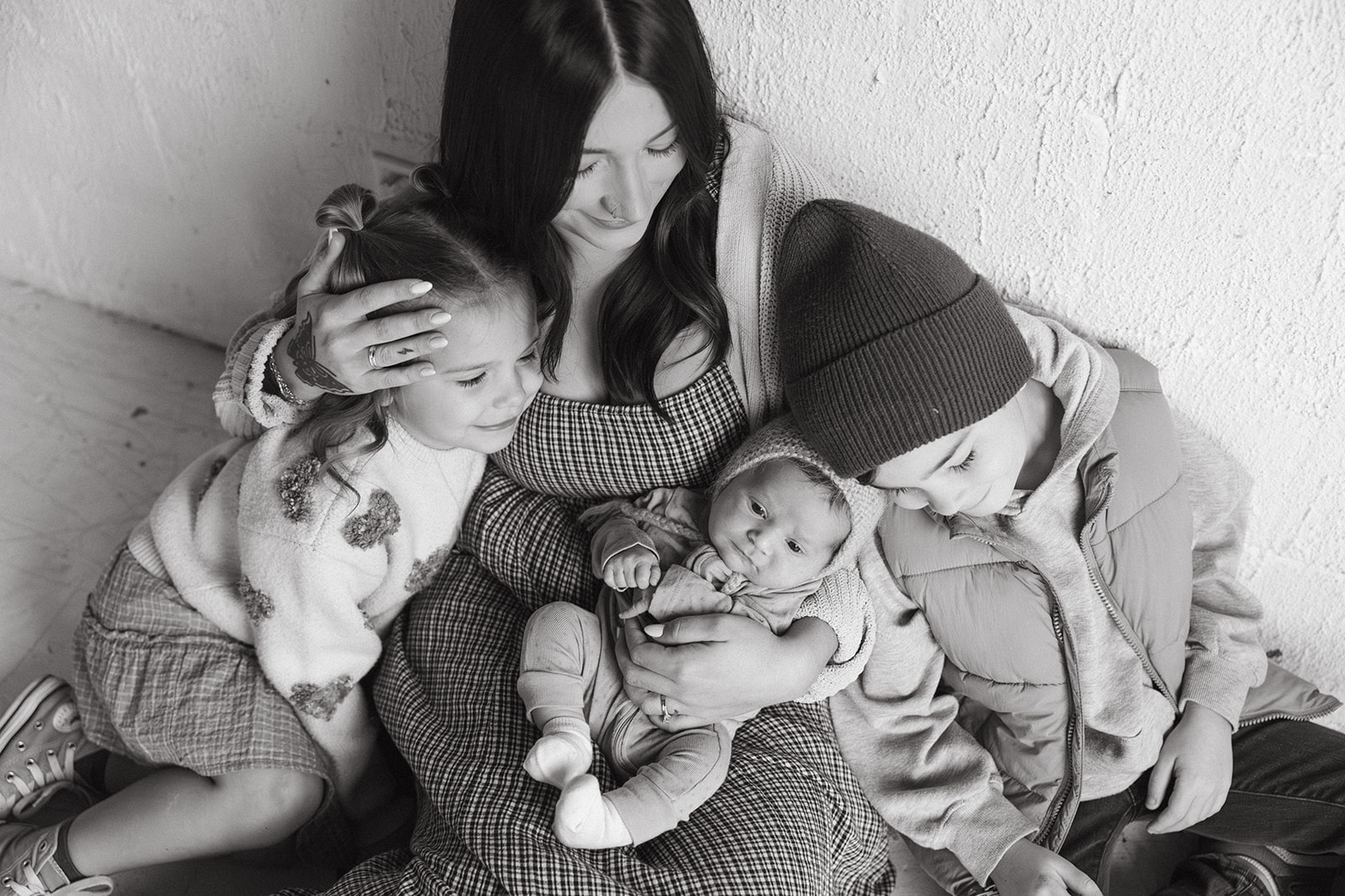 A black and white family photo of kids snuggling with their mom