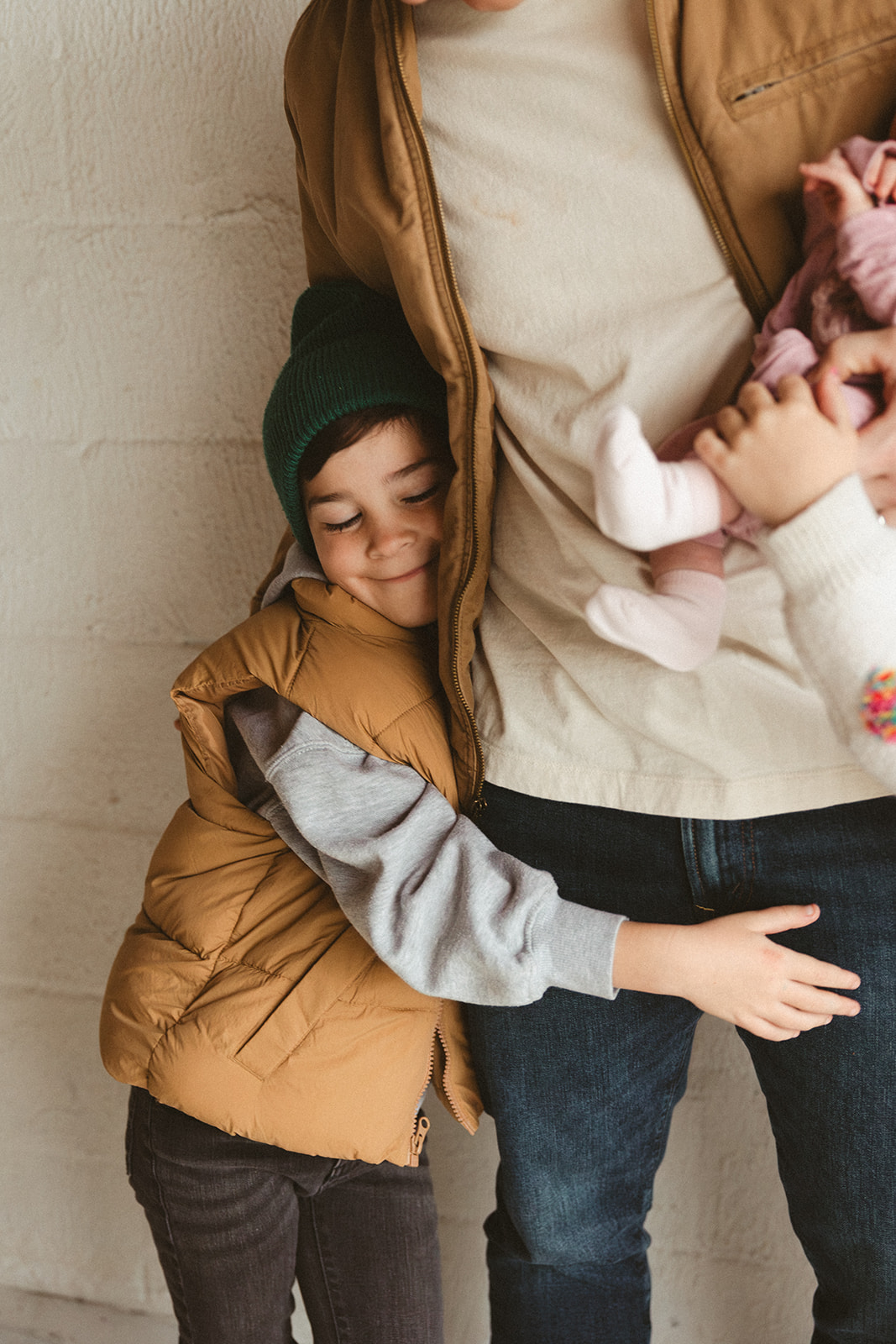 A boy hugging his dad's legs during studio family photos