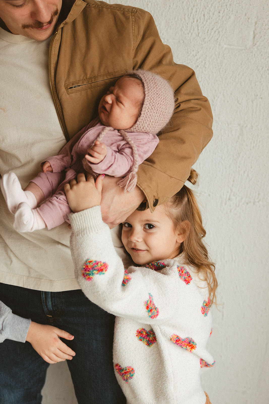 A girl hugging her dad's legs during studio family photos