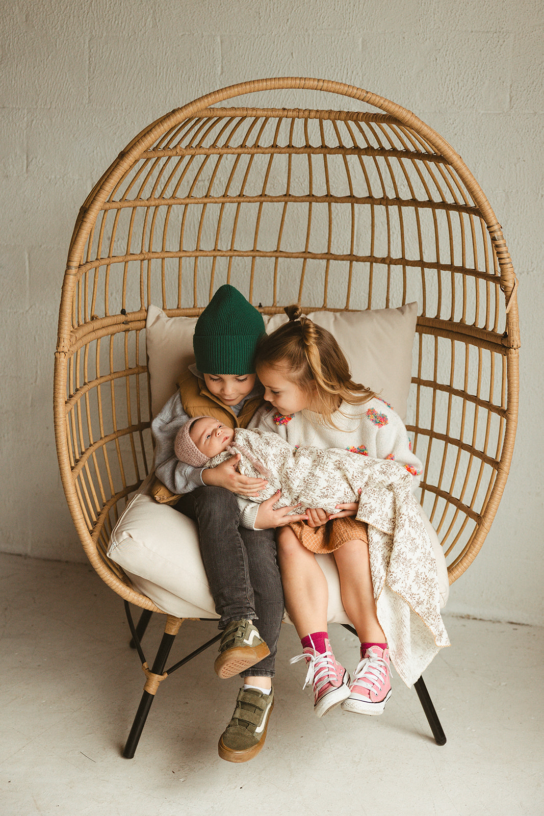 Two siblings holding their newborn baby sister in studio family photos