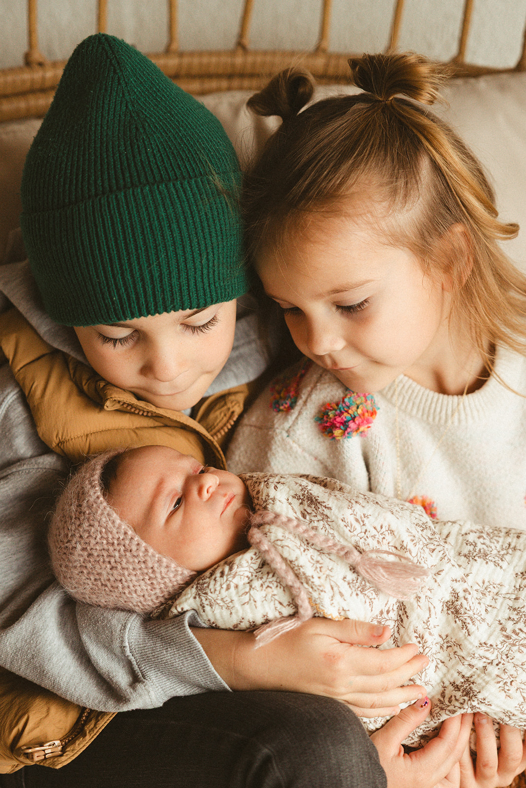 Two siblings holding their newborn baby sister