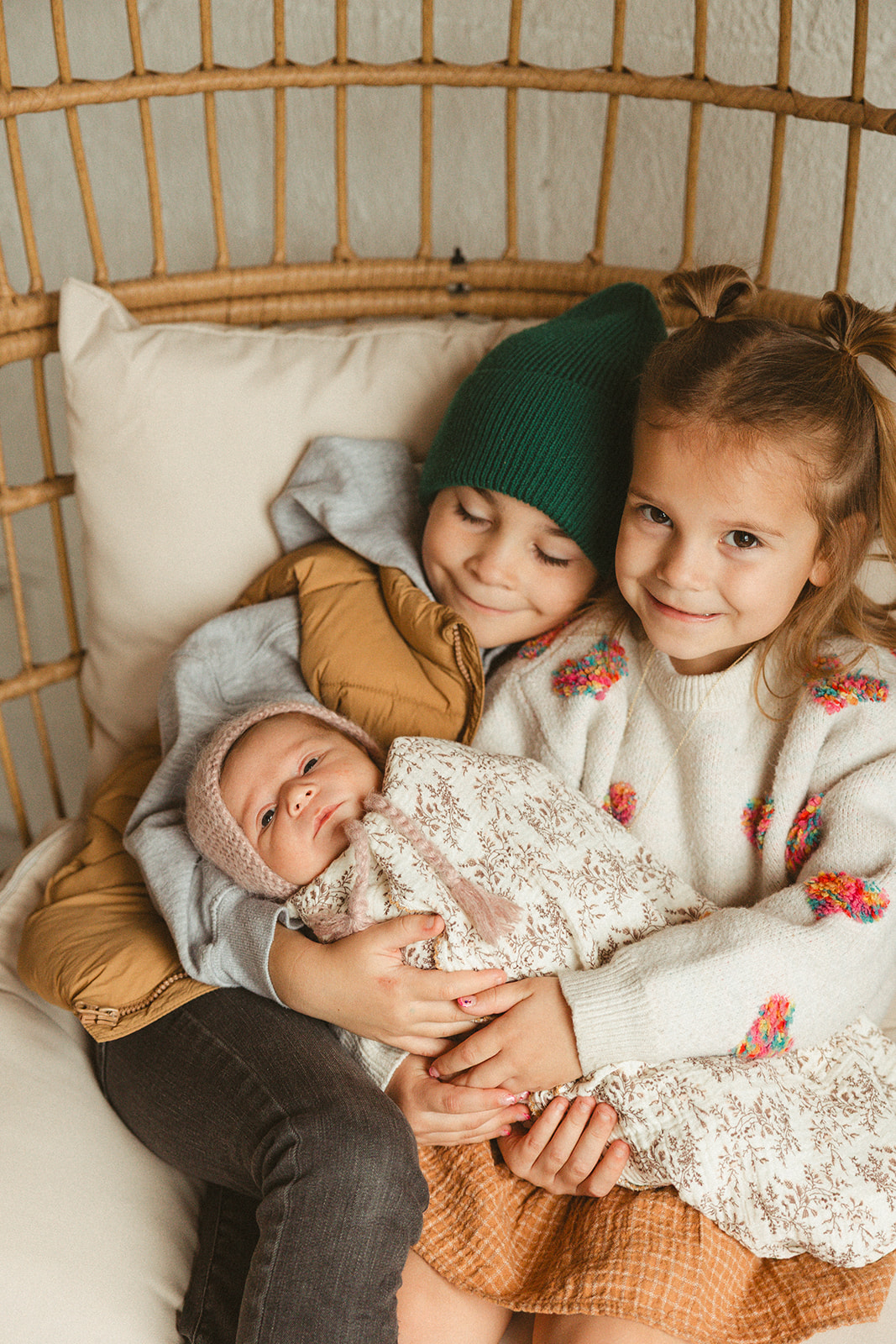 Two kids holding their baby sibling