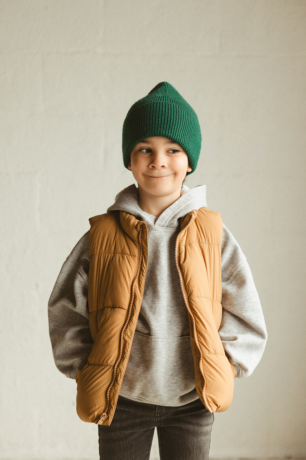 A boy smiling for the camera in a green beanie