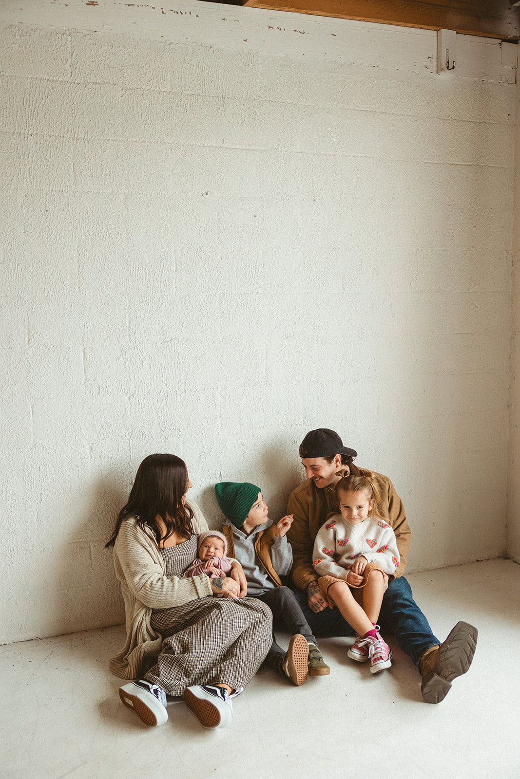 A family sitting on the ground taking studio family photos