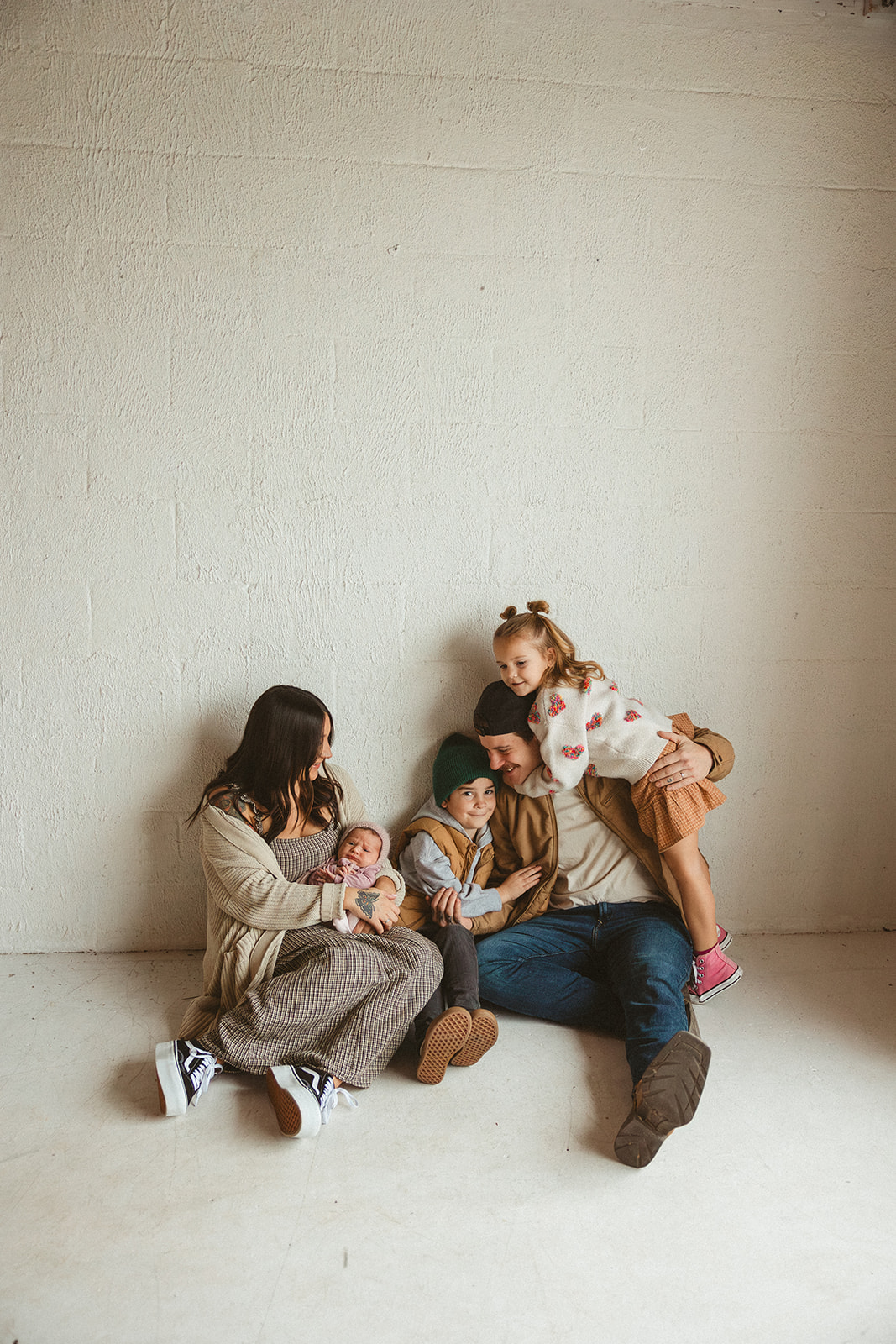 A family sitting on the ground taking studio family photos