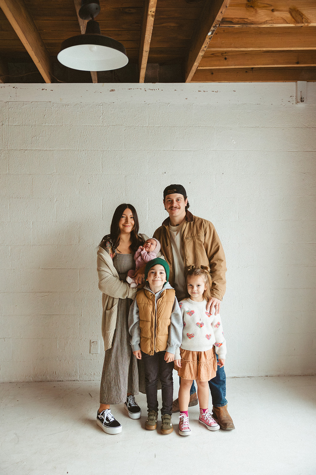 A family posing for studio family photos in front of a white wall